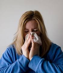 Woman with respiratory illness or allergies blowing her nose.